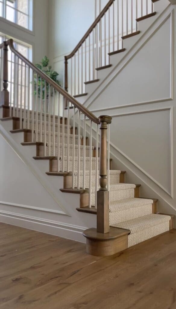 My neutral staircase with white spindles, light wood steps, and trim painted in varying saturation of beige tones, showcasing a designer wall paint idea using layered neutrals.