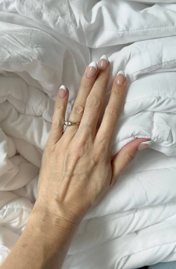 Hand resting on Amazon duvet insert showing smooth fabric quality and lightweight plush feel.