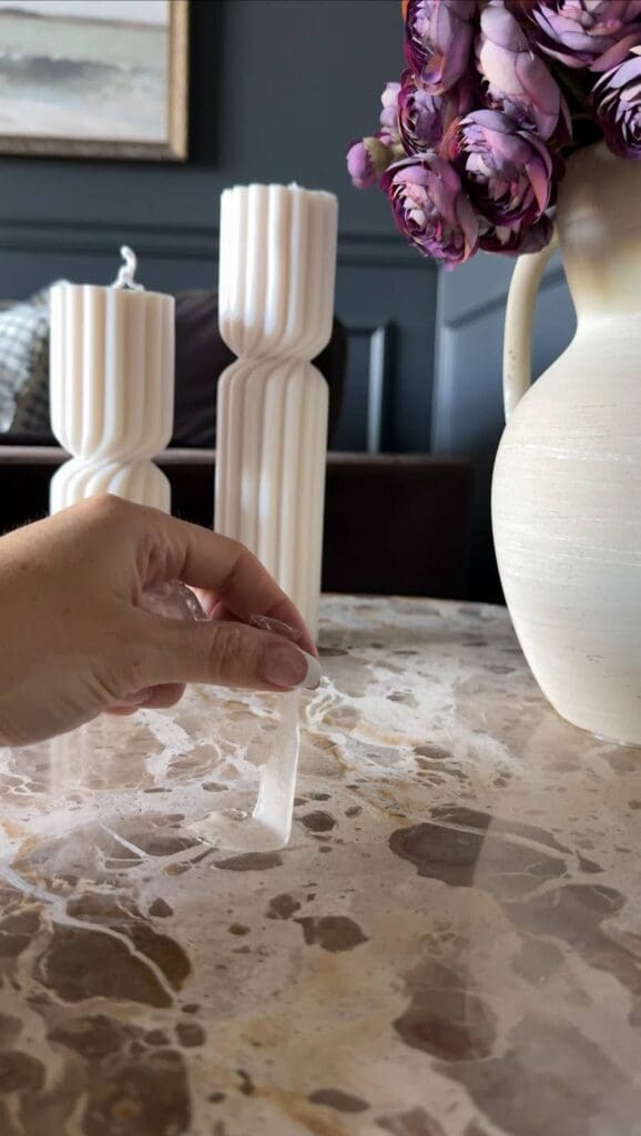 Applying museum gel to secure decorative candles on a marble coffee table