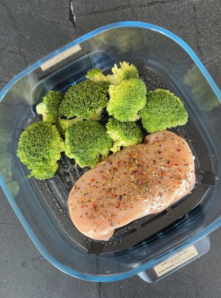 Raw seasoned chicken breast and fresh broccoli ready for cooking in the Ninja air fryer.