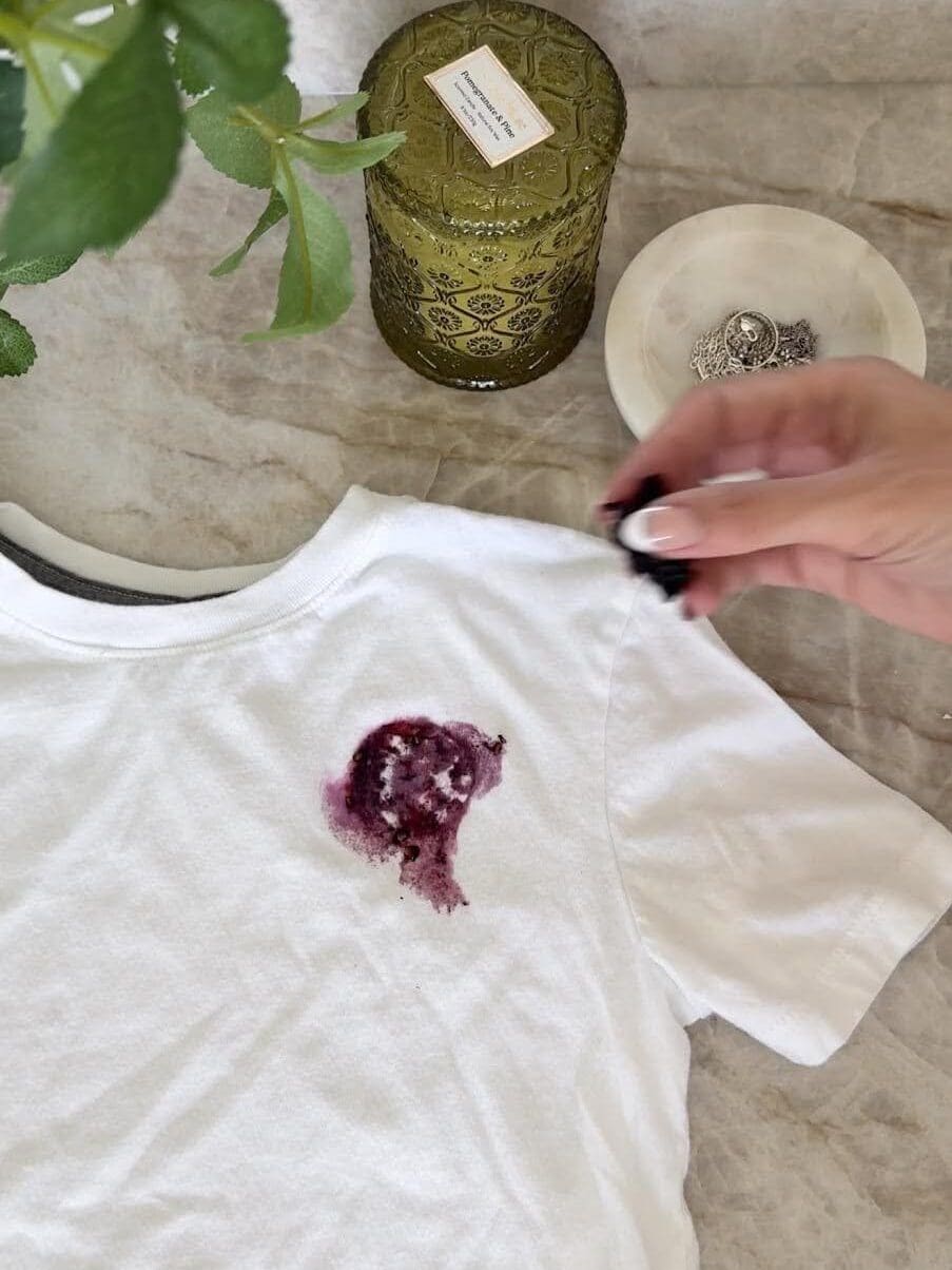 A fresh blackberry stain on a white t-shirt before using laundry spray