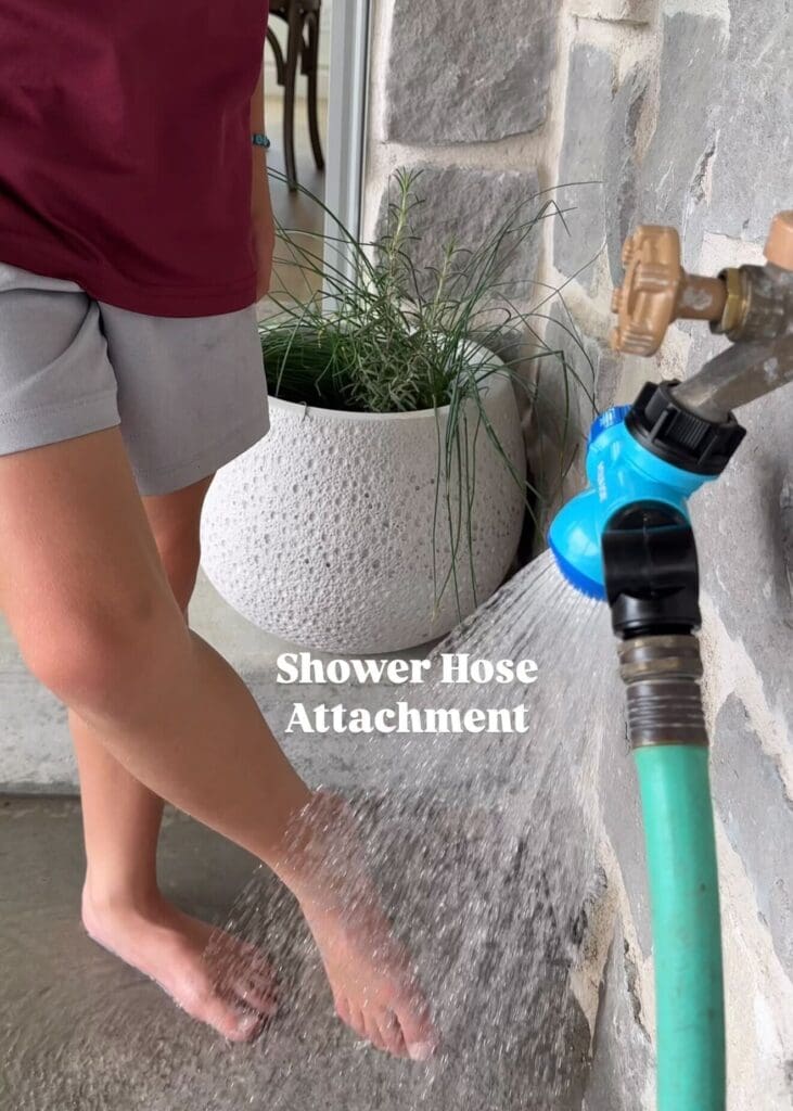 Hose with a spray attachment being used to rinse feet outdoors