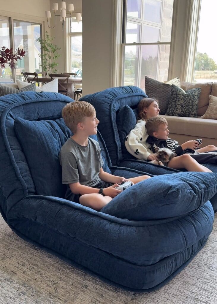Three kids lounging on the navy floor beds during a video game session
