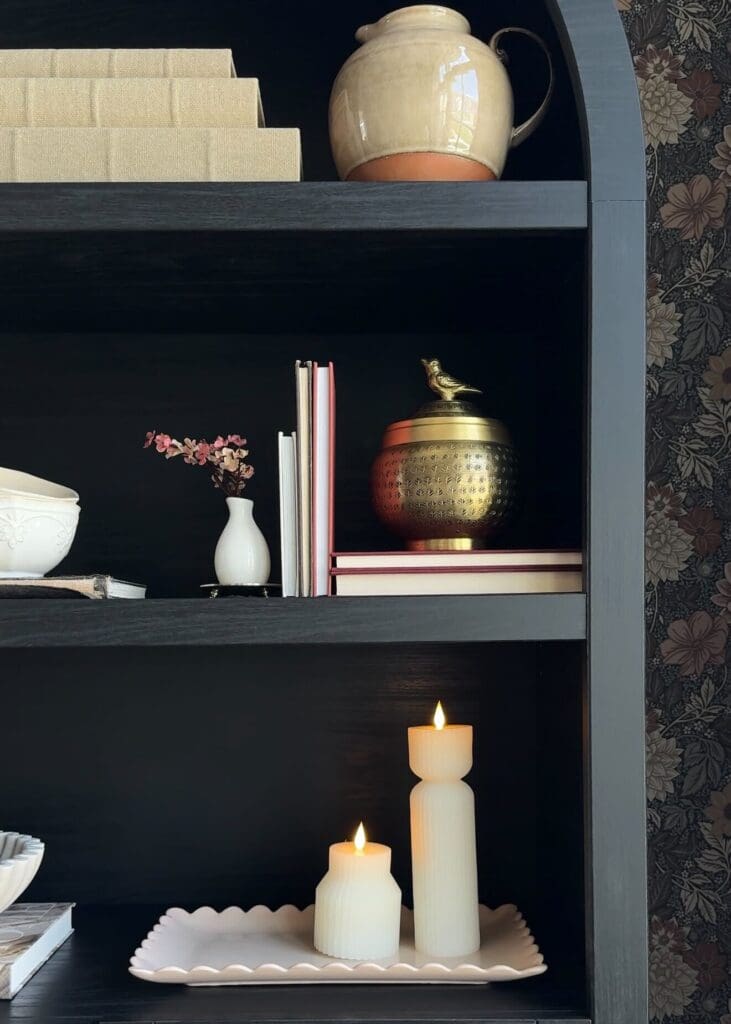 Black bookshelf with flameless candles, books, and mixed metal accents