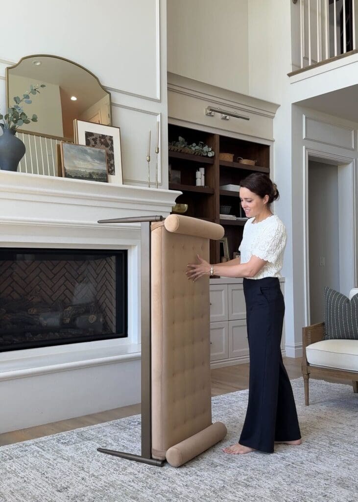 Andrea moving the velvet bolster bench in front of fireplace built-ins.