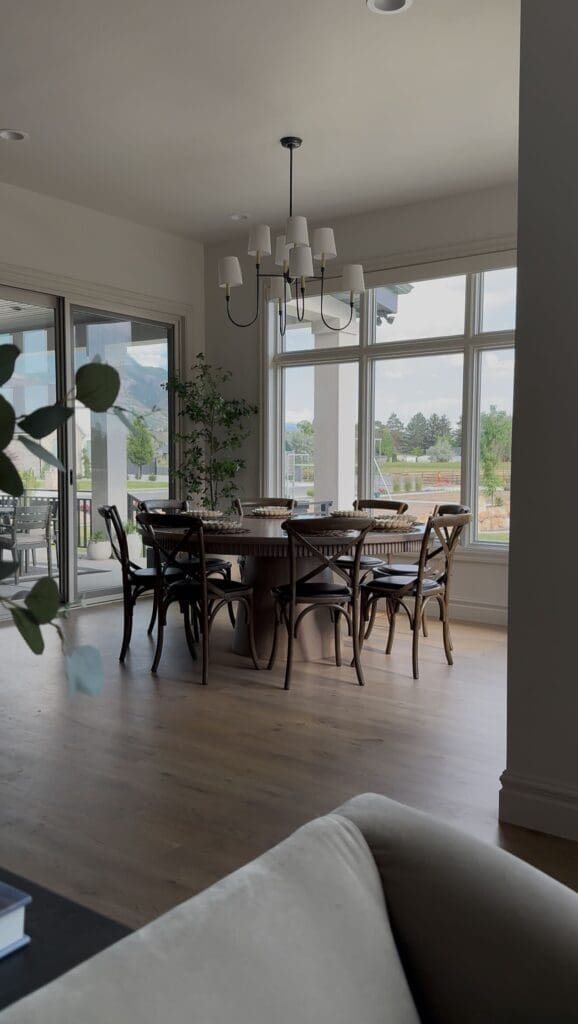 Round fluted-edge dining table in dark wood with eight chairs in a light-filled dining room
