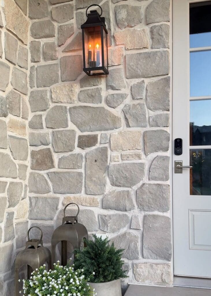 Daylight view of stone exterior with black lantern sconce using a flickering gas-style bulb