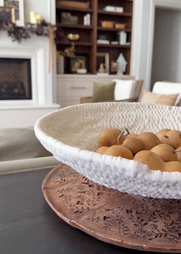 White textured bowl filled with mini dried gourds styled on a living room coffee table.