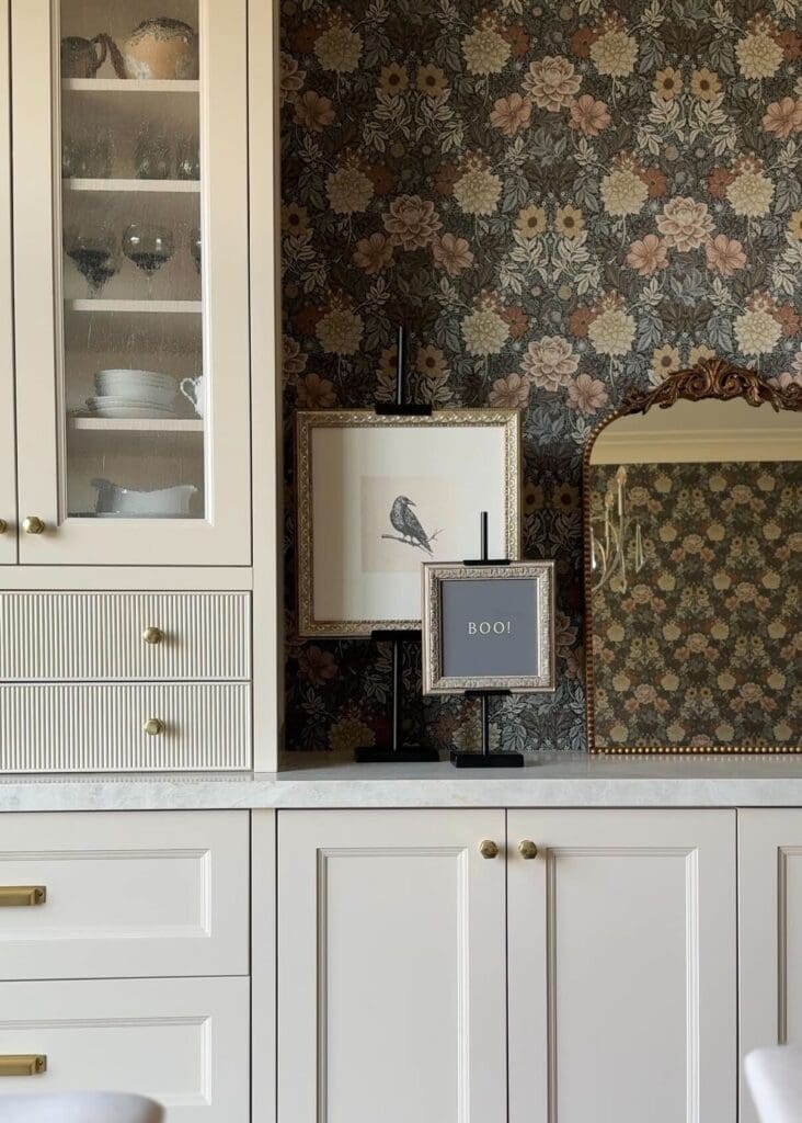 Adjustable art easels styled with framed prints on a kitchen counter with floral wallpaper backdrop