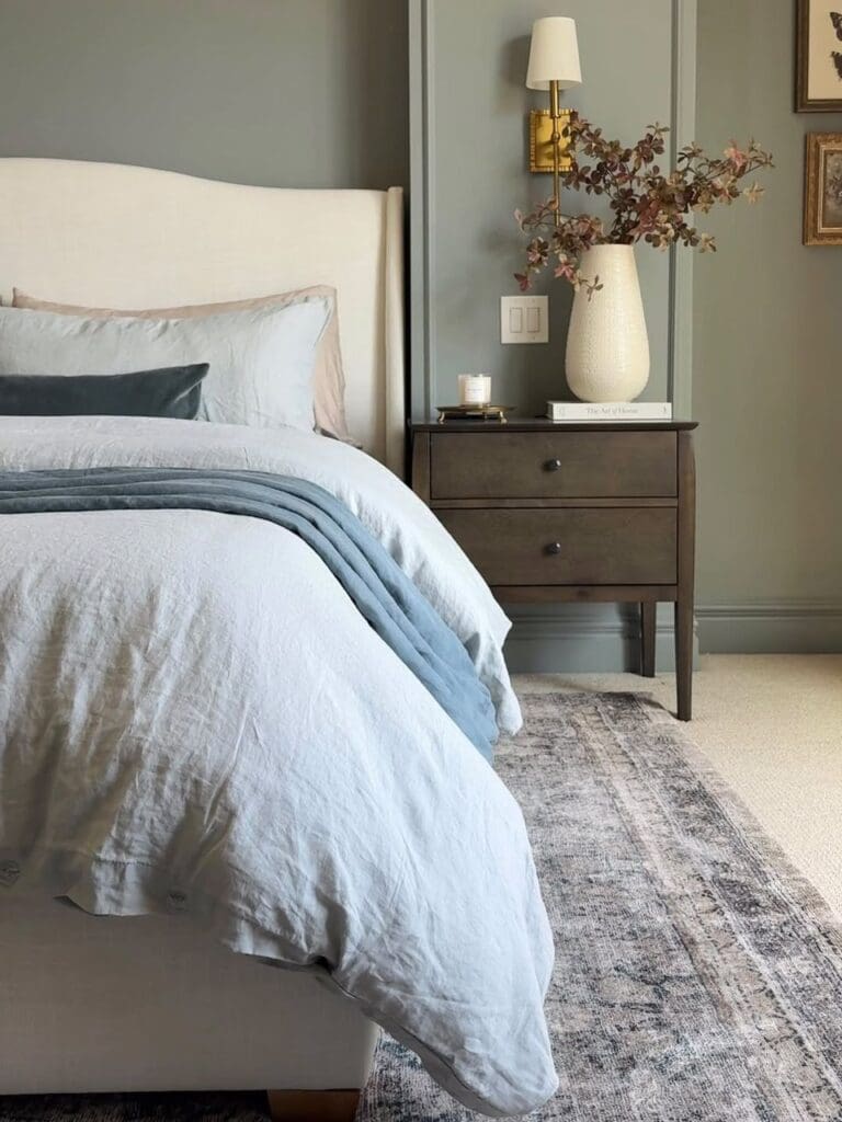 Real bedroom corner with neutral bedding and fall branches.