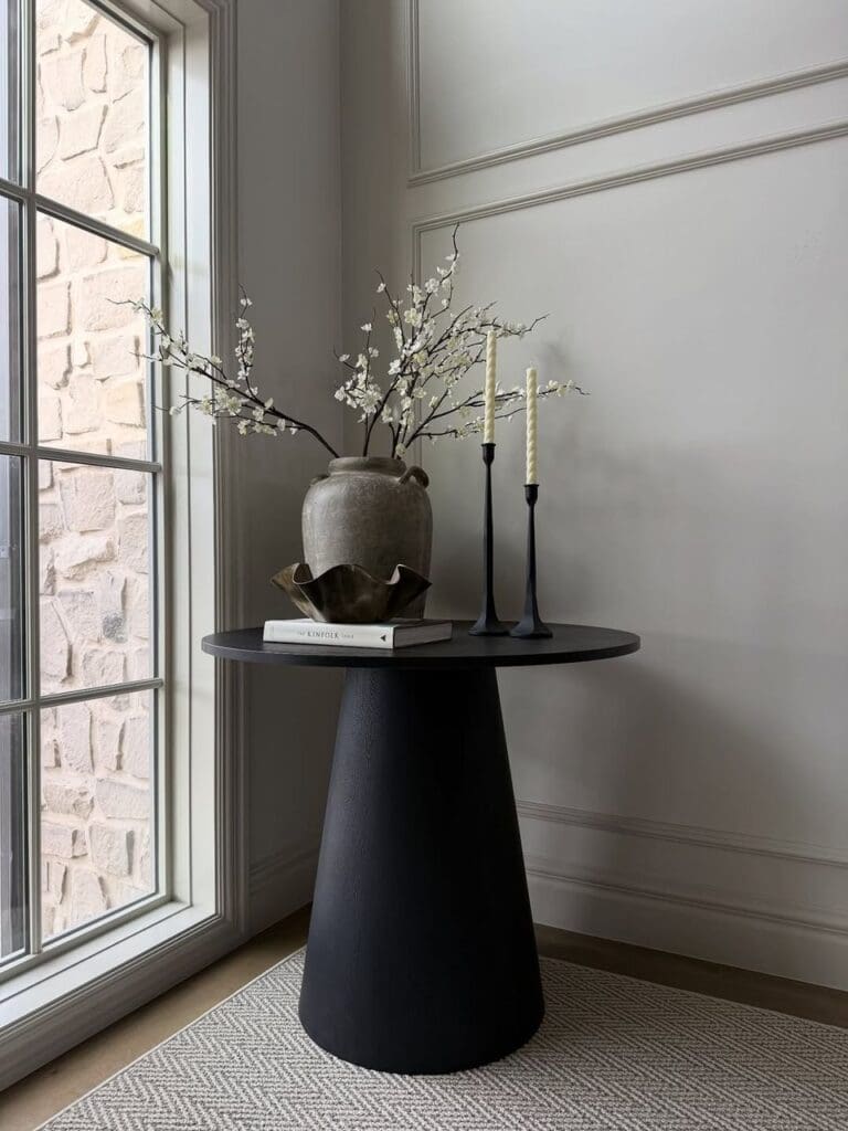Real black pedestal table with vase and branches.