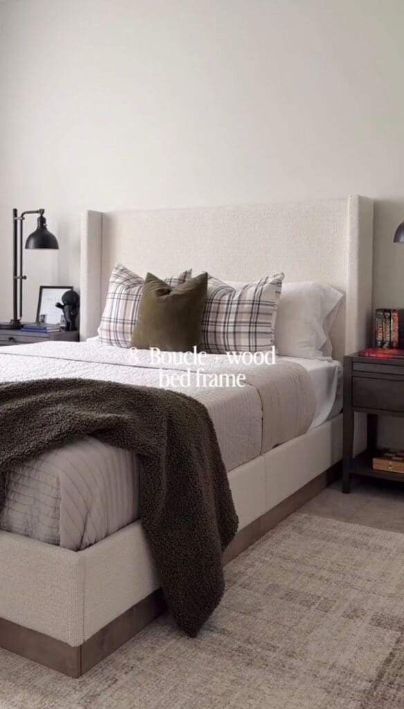 Boucle upholstered bed frame with wood base styled in a neutral bedroom.
